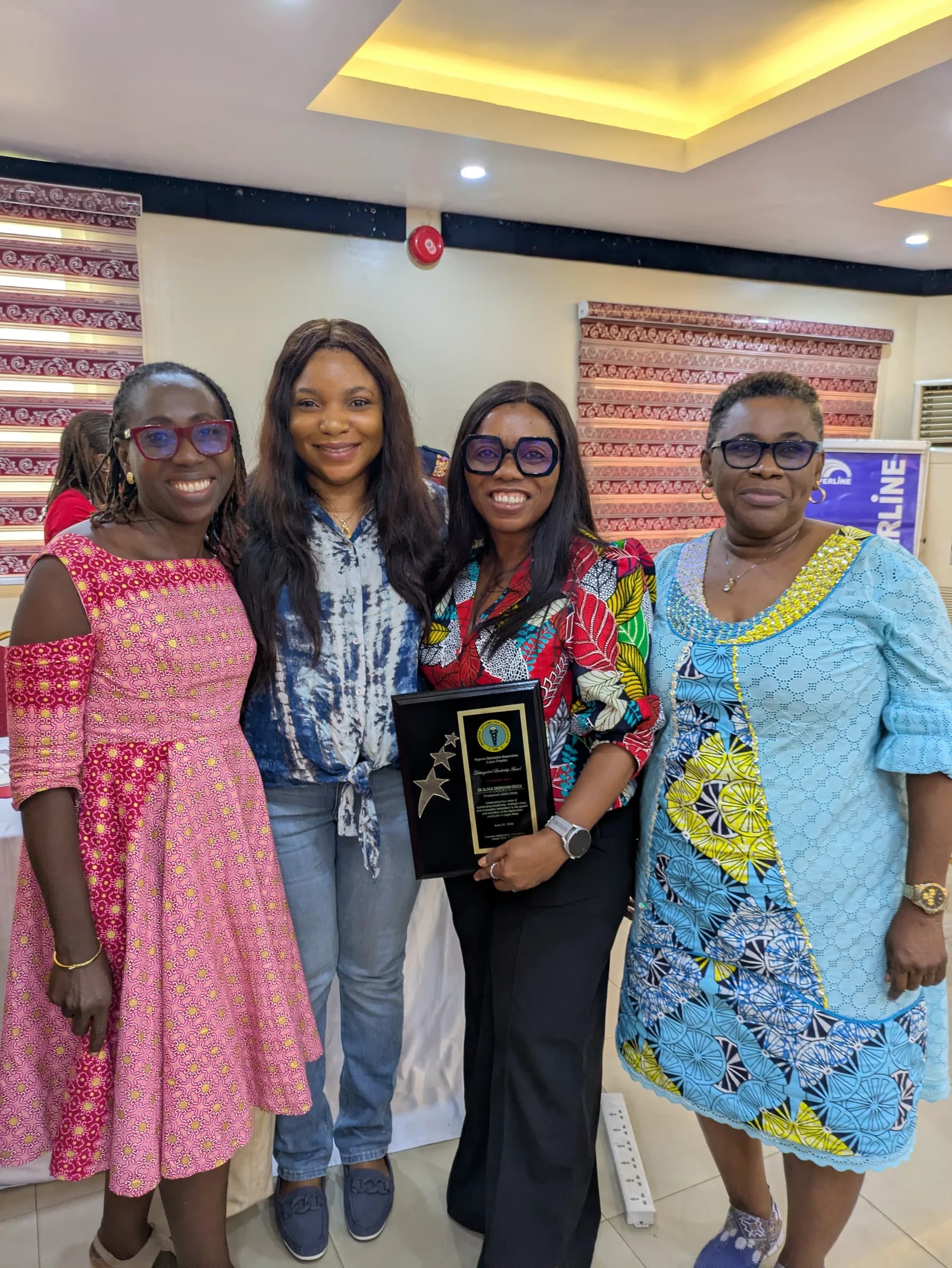 Four members standing together, one holding an award plaque.