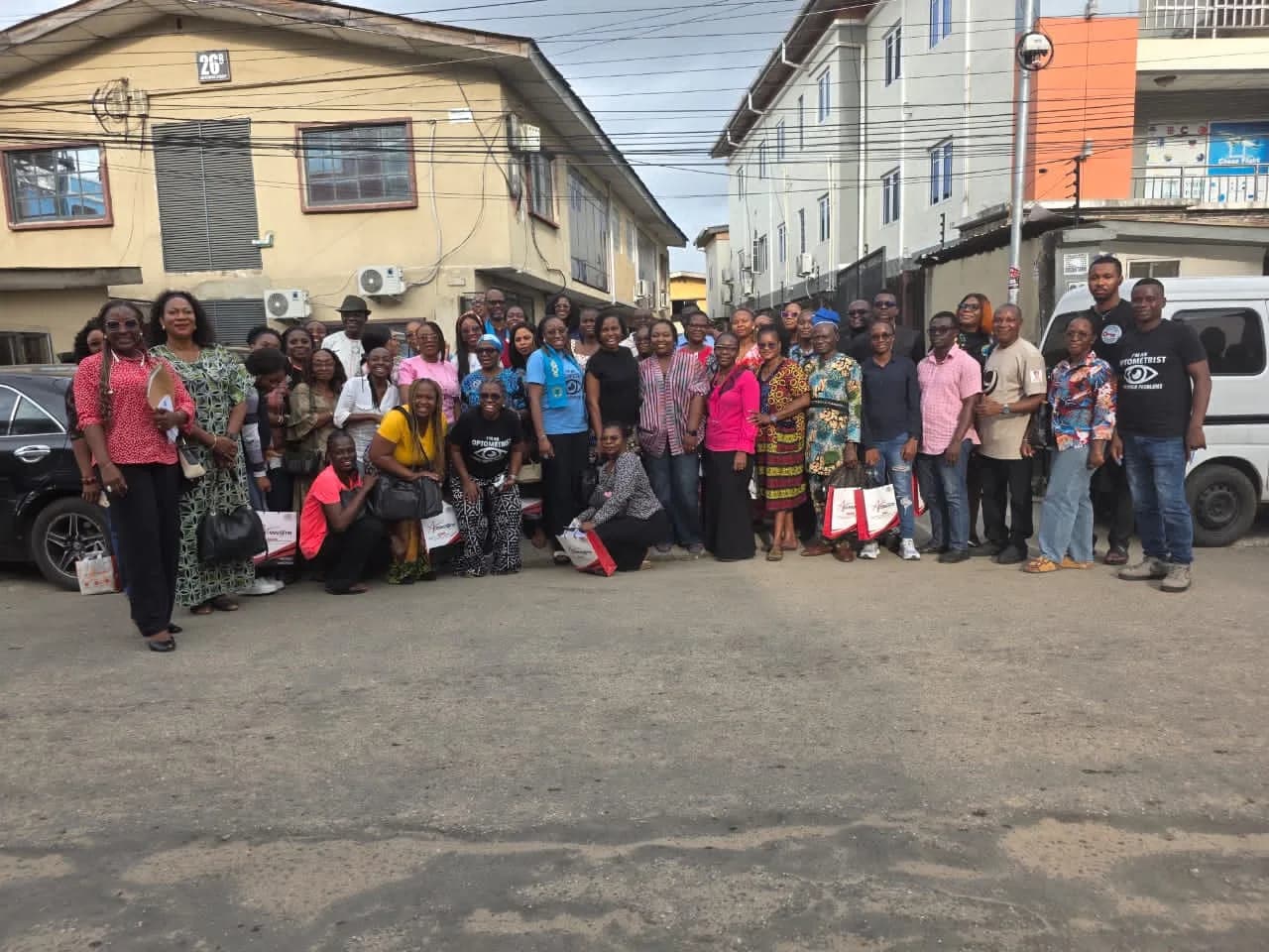 A large group of members and residents photographed on a street between buildings.