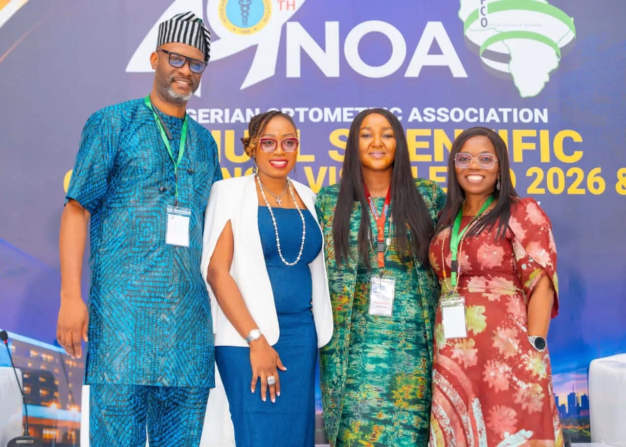 Four members standing together in front of the NOA conference banner.