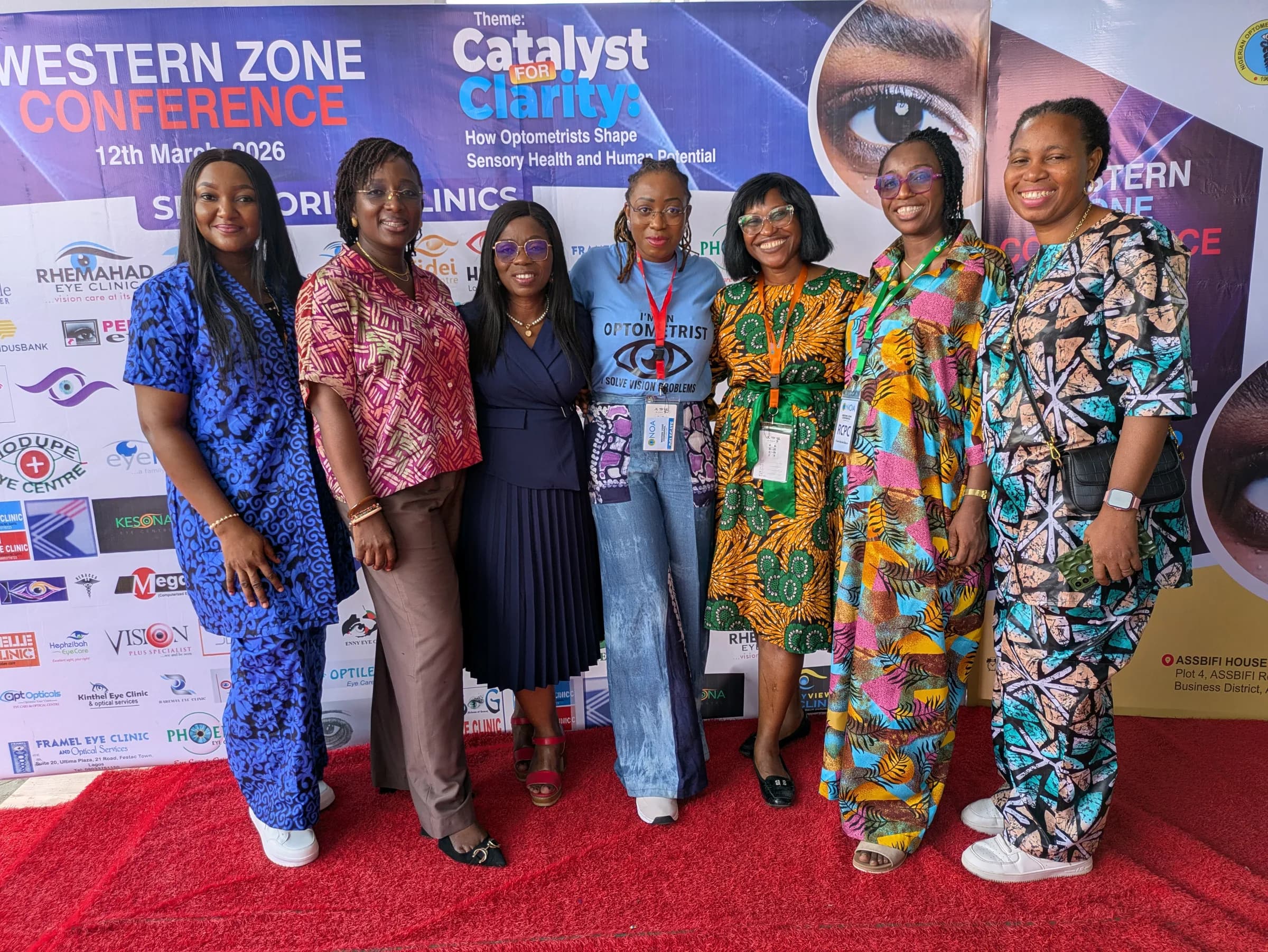 Six members standing together on the red carpet at the conference entrance.