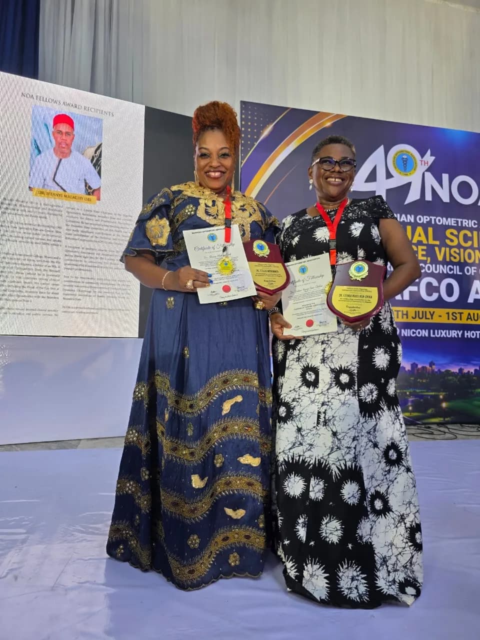 Two members holding framed certificates and a plaque.