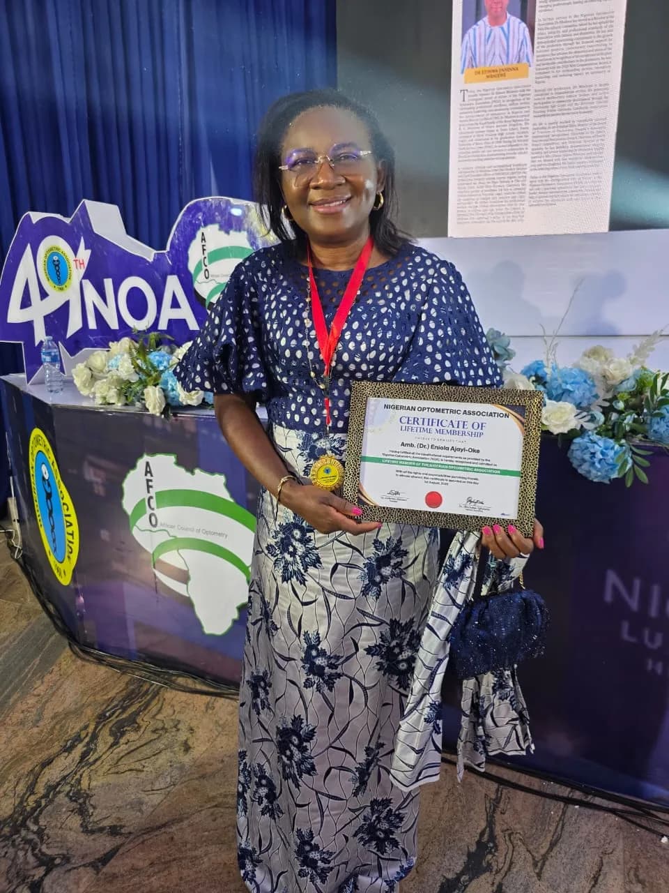 A member holding a certificate of recognition beside the AFCO stand.