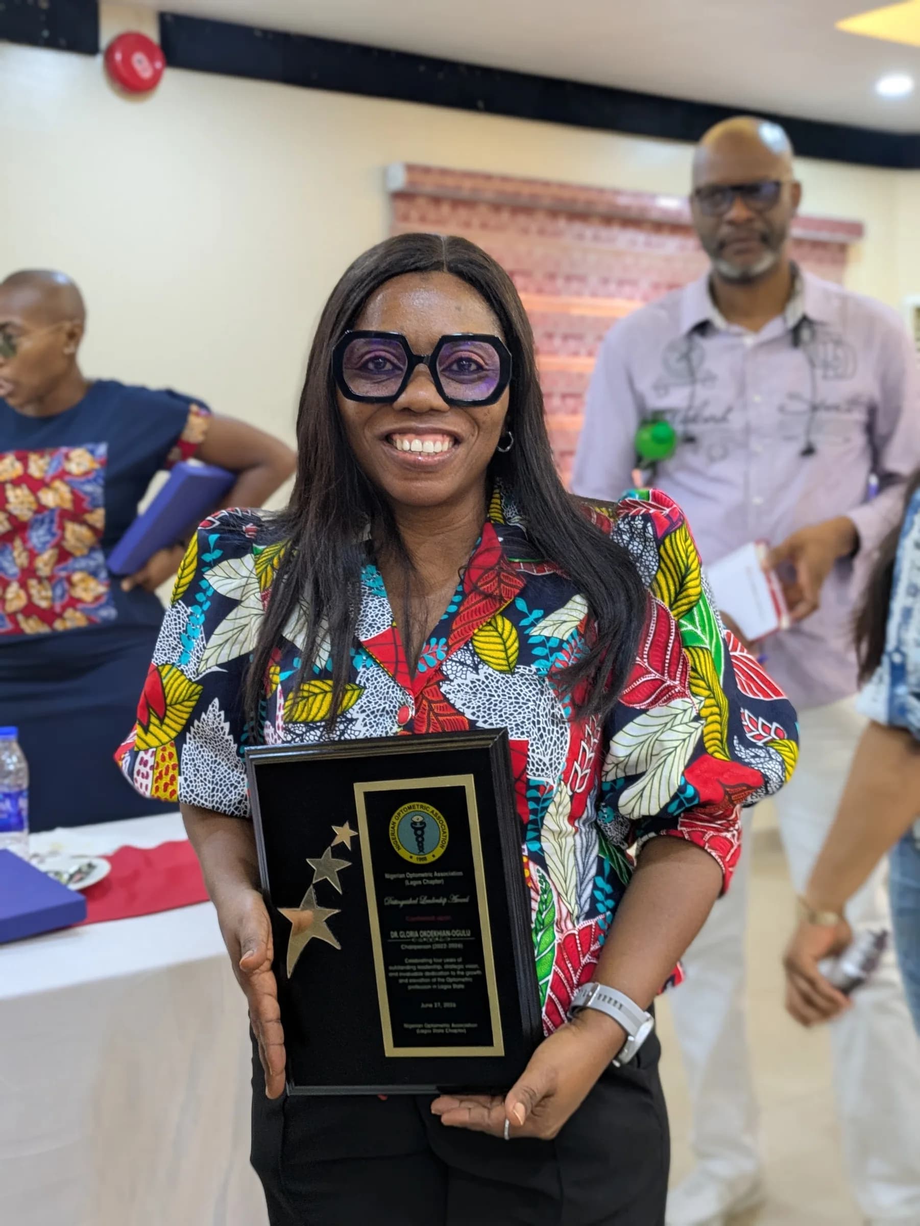 A member holding a black award plaque and smiling at the camera.