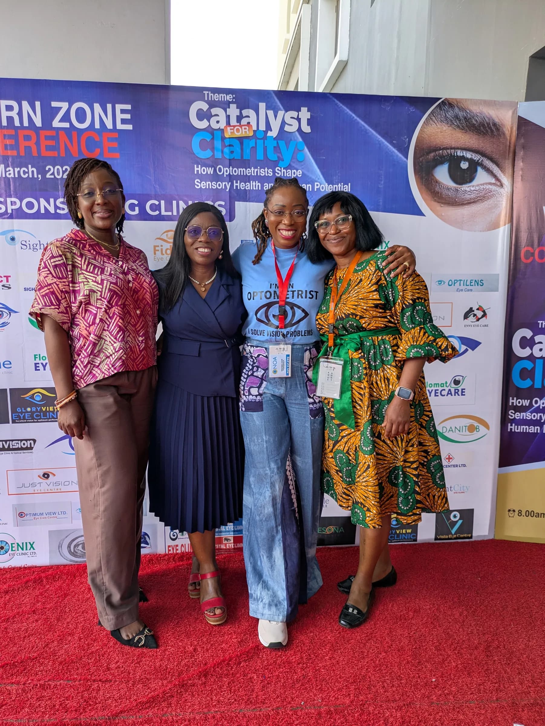 Four members on the red carpet in front of the conference backdrop, which reads "Catalyst for Clarity".